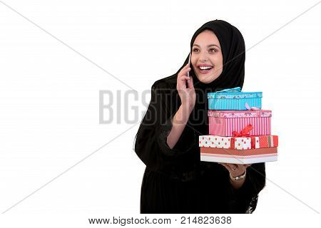 Happy young muslim woman with shopping bag and gift boxes isolated over white background.