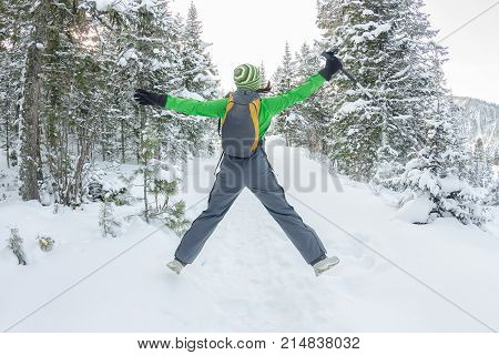 Happy Tourist Girl With A Backpack Walks In A Winter Forest Among Large Trees