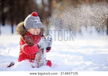 Little Boy In Red Winter Clothes Having Fun With Snow