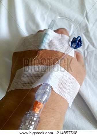 Patient Hand With The Tube Of Normal Saline Infusion On White Cloth Background