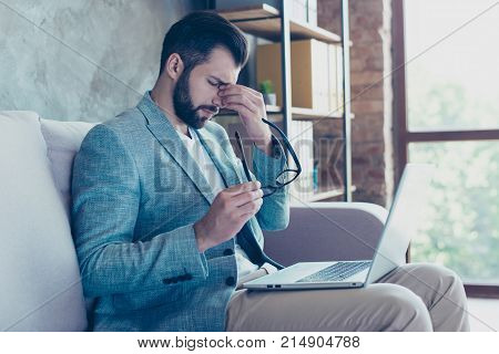 Side View Portrait Of Attractive Young Lawyer,  Taking Off His Spectacles, Having Computer On His Le