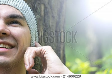 A young man sits under a tree and listens to music
