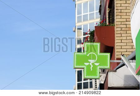 Green cross pharmacy sign with snake symbol on the building