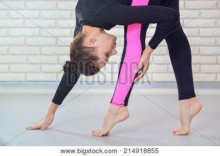 Young elegant woman dancer stretching at gym standing on toe, closeup portrait. Fitness and lifestyle concept