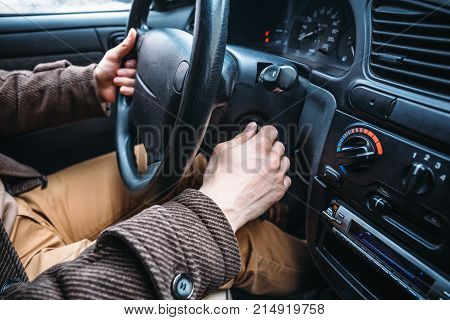 Man driver hand puts car key to keyhole to start his automobile, toned