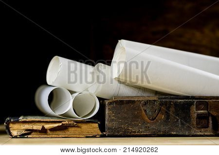 Old Rolls And Plans In Folded Paper Rolls. Old Book And Case. Documents On An Old Wooden Table.