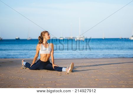 Girl splits on the beach. Yoga on the beach in the morning