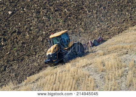 TUSCANY, ITALY - SEPTEMBER 20, 2017: The catarpillar Challenger MT765D on plowing of the field in the sunny September afternoon