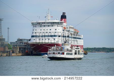 HELSINKI, FINLAND - JUNE 11, 2017: The tourist boat passes by the sea ferry 