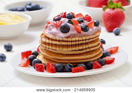 Pancakes with fruit yogurt fresh strawberry and blueberry on white plate