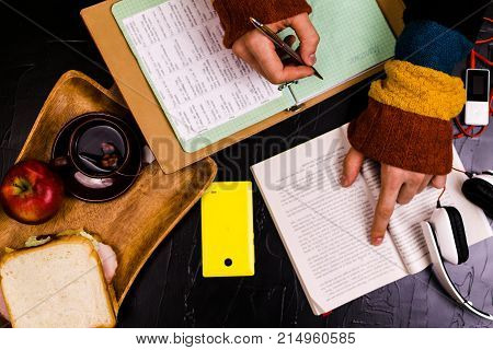 A man reads translates the text. Sandwich headphones pencils notebooks. Still life black background.