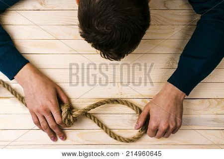 A man holds a loop of rope in his hands. A mental health day.