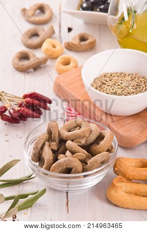 Italian taralli with olives and spices on wooden table.