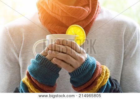 A young man holding a Cup of tea and lemon. Cold cold disease.