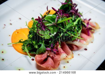 Salad With Fried Bacon Herbs And Orange Fruit In White Plate With Black Background