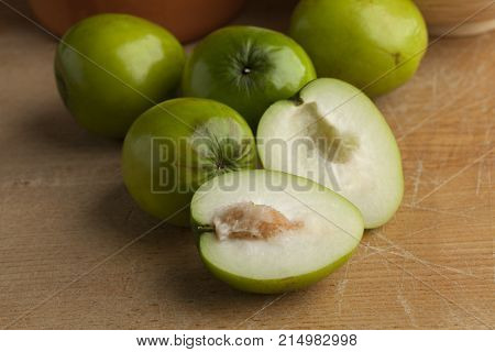 Fresh green whole and half Ambarella fruit with a fibrous pit