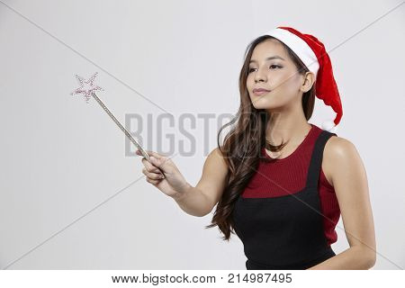 woman with santa hat holding a magic wand