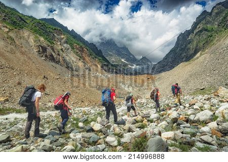 Group of hikers with backpacks climb up to the glacier to the peak of mountain. Caucasian mountains Georgia Svaneti region.