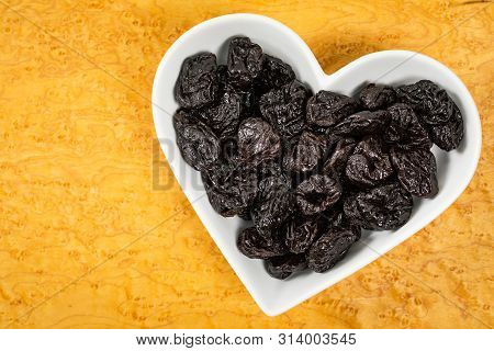 Dried Plums Pitted Prunes In Heart Shaped Bowl Background. Selective Focus.