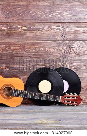 Musical Instuments On Vintage Wooden Background. Acoustic Guitar And Two Vinyl Records On Wooden Boa