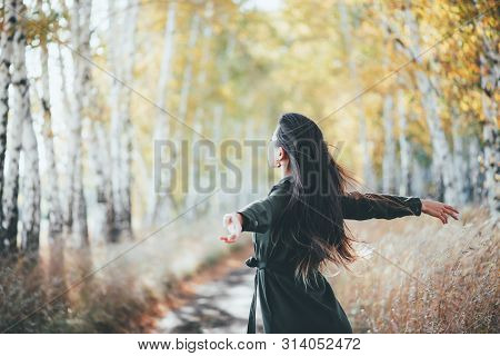 Dreamy Beautiful Girl With Long Natural Black Hair Flies On Bokeh Background Of Autumn Yellow Leaves
