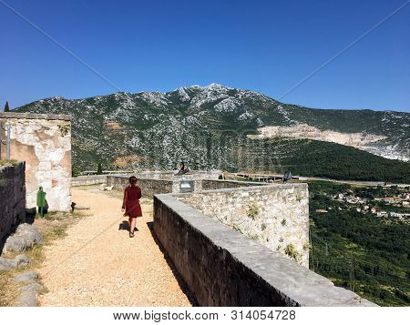 A Young Female Tourist Walking Around The Medieval Fortress Of Klis On A Beautiful Summer Day.the Kl