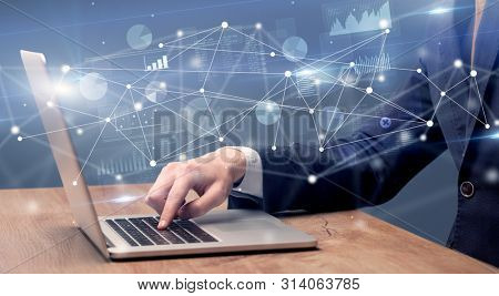 Businessman typing on laptop with linked reports charts grapghs around