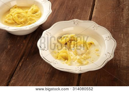 Tortellini Served With Broth And Cream Sauce And Cheese, Italian Food On A Dark Rustic Wooden Backgr