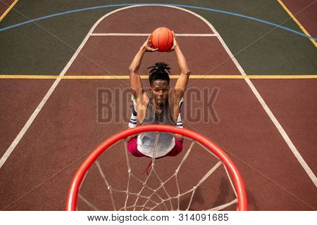 African young basketballer making effort while throwing ball in basket