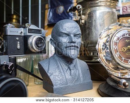 Krasnodar, Russia - July 5, 2019: Sculpture Of Vladimir Lenin. Old Soviet Zenit-e Camera, Clock And 