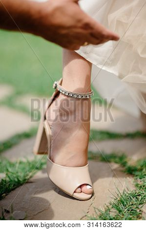 The Legs Of The Bride In A Wedding Dress In Shoes Close Op