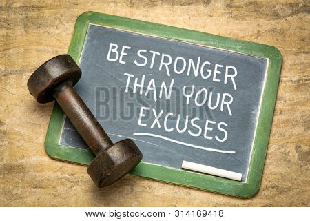Be stronger than your excuses - fitness motivation quote on a slate blackboard with qn iron dumbbell
