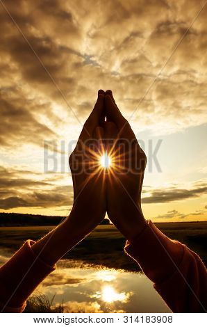 Tin Namaste Close-up, The Sun Shines Between The Fingers With Stunning Rays. Silhouette Against The 