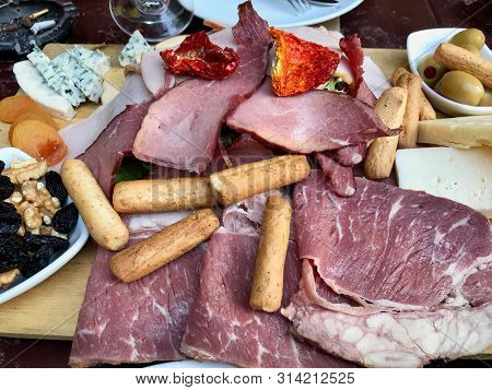 Red Wine And Assorted Cheese Plate, Smoked Beef, Ham, Salami, Green Olives With Fruit.