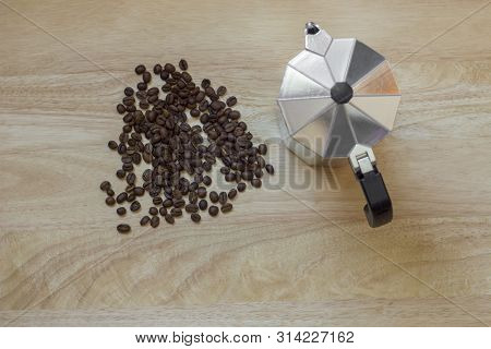 A Pile Of Roasted Brown Coffee Beans On The Light Wooden Surface Of The Table And A Geyser Coffee Ma