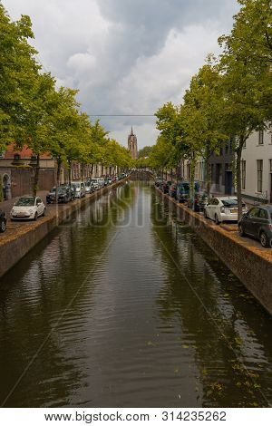 Delft, The Netherlands - July 19 2019 : View Of Historic Oude Canal Leading To  View Of The  Oude Ke