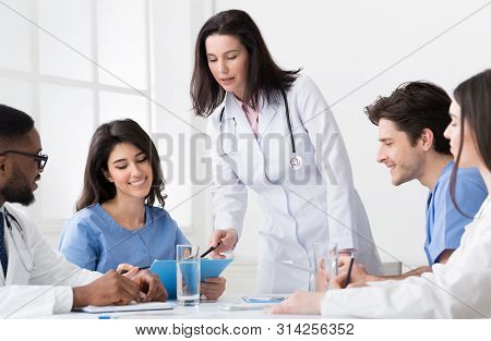 Chief Doctor Discussing Diagnosis With Interns And Practitioners At Concilium In Clinic