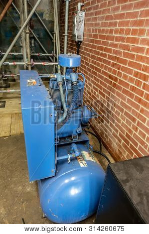 Industrial Grade Air Compressor Next To Masonry Brick Wall