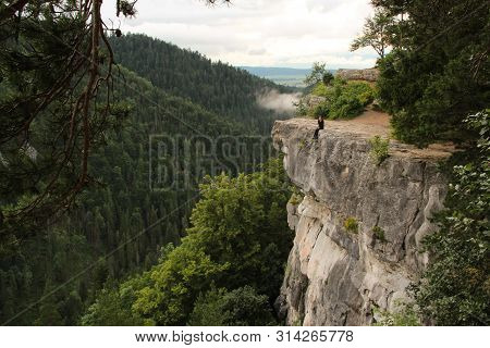 A Man Standing On A Ledge Just Above The Abyss