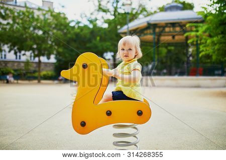 Adorable Toddler Girl Having Fun On Spring Rider On Playground. Outdoor Activities For Kids