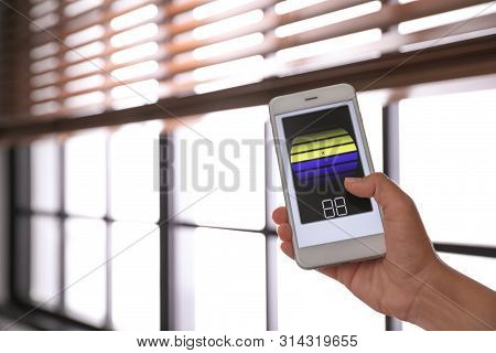 Woman Using Smart Home Application On Phone To Control Window Blinds Indoors, Closeup. Space For Tex