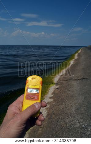Geiger counter near storage pool near of hydroelectric station. After Chernobyl disaster - collection active sediments.The radiometer gives readings in micro-Sieverts. July 29, 2019.Kiev ,Ukraine