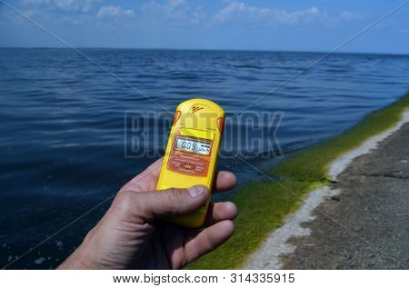 Geiger counter near storage pool near of hydroelectric station. After Chernobyl disaster - collection active sediments.The radiometer gives readings in micro-Sieverts. July 29, 2019.Kiev ,Ukraine