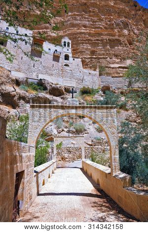 Wadi Kelt near Jerusalem. On the steep wall of the gorge - Monastery of St. George the Victorious. The massive stone gate on the mountain road leading to the temple