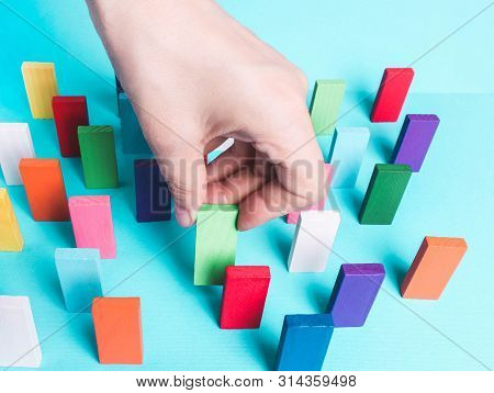 Female Hand Puts In A Row Colored Dominoes.