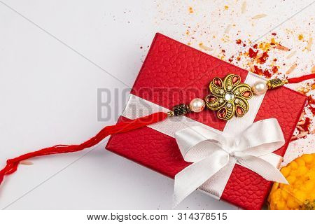 Indian Festival - Rakhi On Red Gift Box With Sprinkle Rice, Kumkum, Haldi On White Background And Sw