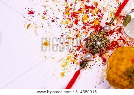 Indian Festival - Close View Of Elegant Rakhi, Sweets, Cardamom And Indian Currency With Spread Rice