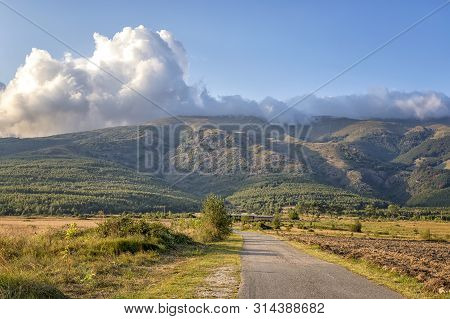 Straight ?sphalt Road Going Through A Valley To The Mountain