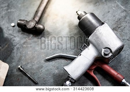 Pneumatic Wrench And Hammer On Concrete Floor In Auto Repair Shop. Car Wheel Repairing Concept