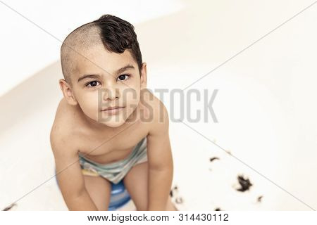 Six-year Boy At Haircutting At Home. Father Cut Half Of The Son's Hair Off At The Bathroom
